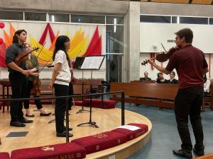 Man demonstrates on violin to student quartet