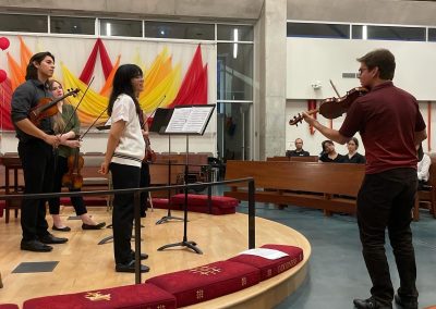 Man demonstrates on violin to student quartet