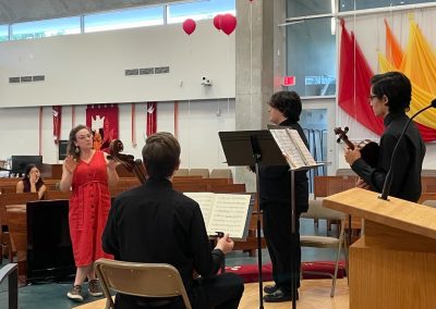 Woman in orange dress talks with students onstage
