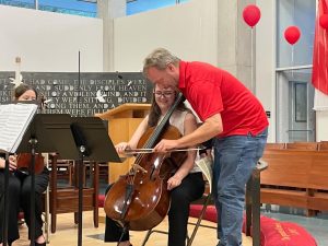 Man moves student's bow on the cello