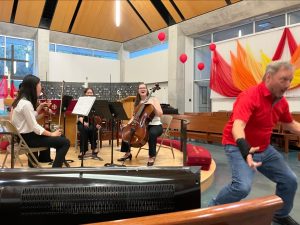 Man strikes sumo pose for audience in front of laughing student quartet