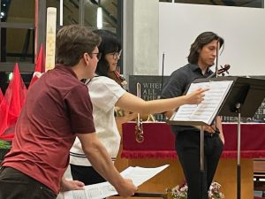 student violinist points to sheet music while teacher looks on
