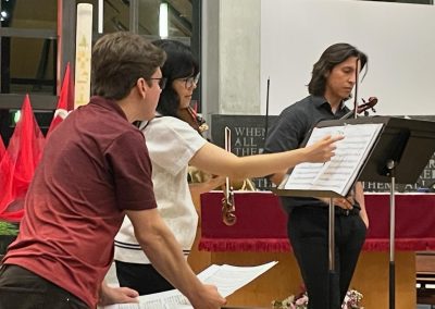 student violinist points to sheet music while teacher looks on