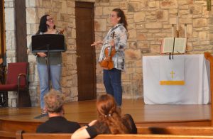 Woman talks with student violinist on stage