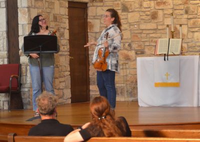 Woman talks with student violinist on stage
