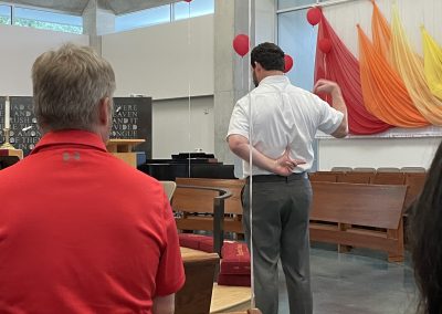 Man in white shirt with back turned pointing at a spot on his back