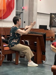 Woman with short hair gestures while speaking from seat