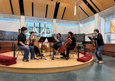 Young string quartet receives to instruction in front of an audience.