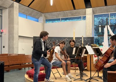 Young string quartet receives to instruction in front of an audience.